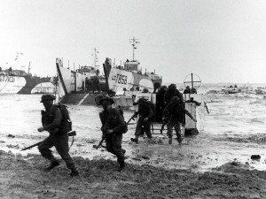 Chaotic scenes as Allied troops leave their landing crafts to face the German machine guns. The film intercuts shots of Tom’s body being removed from his craft with archive footage of dead and wounded soldiers being returned to Britain. 