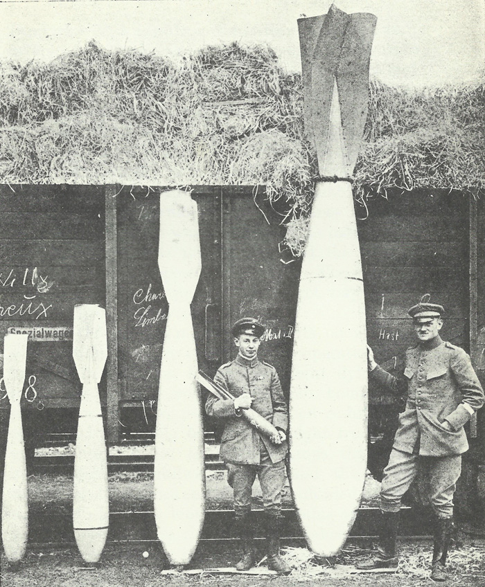 The range of bombs carried by Gothas and Giants. From left to right are 50kg, 100kg, 300kg, and 1,000kg bombs, with the man in the centre holding a 12.5kg bomb.