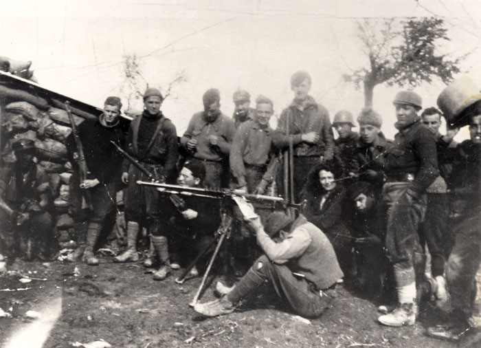 Black and white photograph of Orwell, standing sixth from the left with a rifle slung over his arm, on the Aragon front of the Spanish Civil War, 1937.