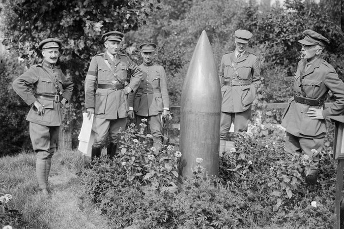 Black and white photograph of William Beach Thomas and soldiers examining a dud shell on the Western Front. 